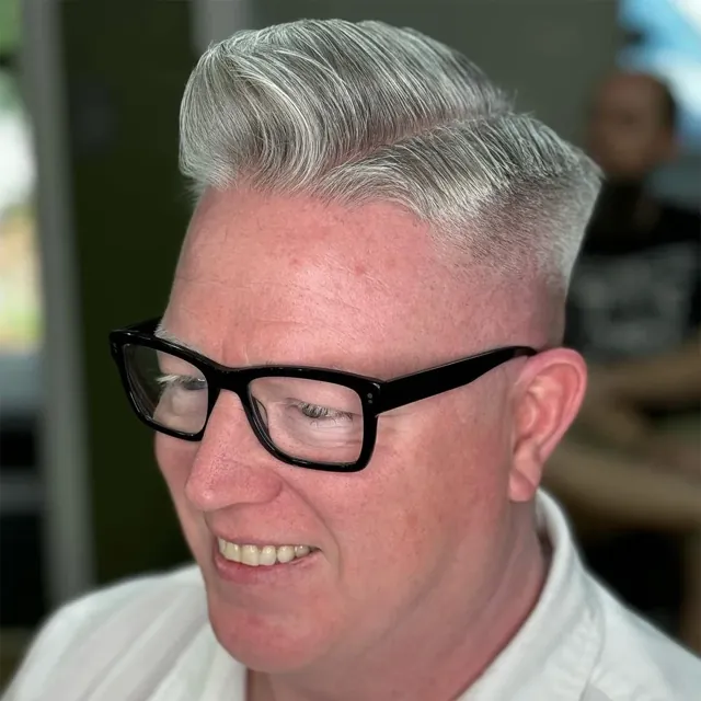 Silver pompadour with a high skin fade.