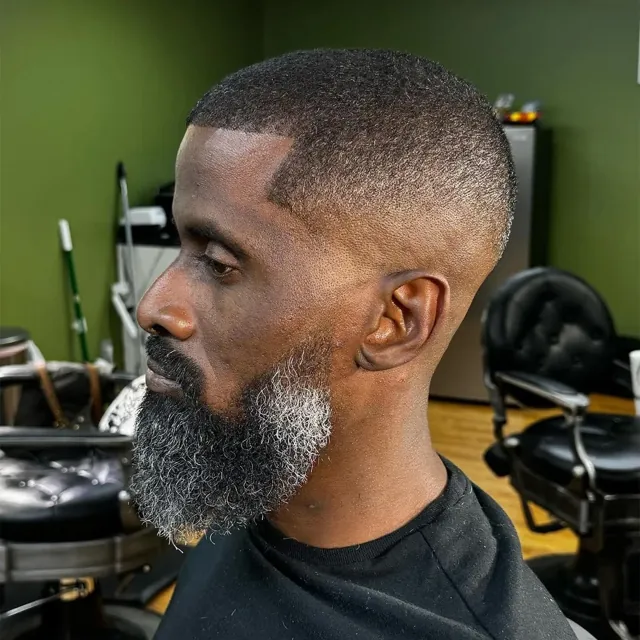 Tight buzz with a lined-up salt-and-pepper beard.