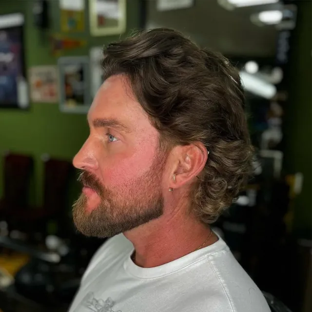 Long wavy hair with a trimmed beard.